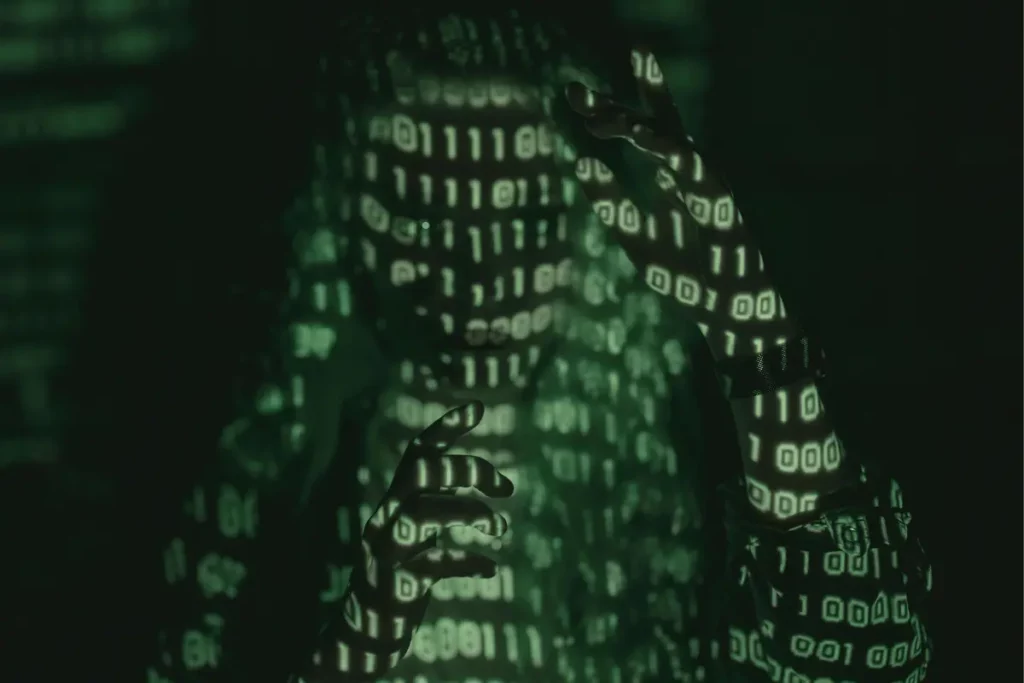 Person covered in green binary code projections, creating a futuristic and digital visual effect in a dark environment.