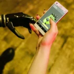 A person interacting with a robotic arm using a smartphone.