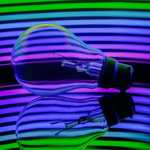 Light bulb reflecting vibrant neon stripes, symbolizing creative energy.