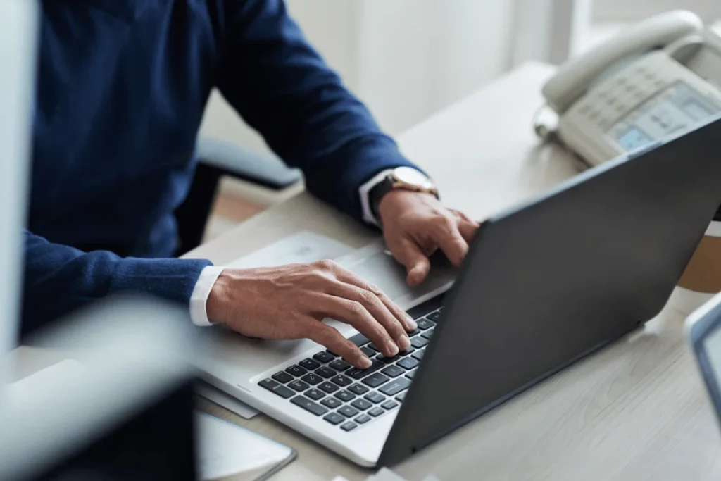 A person typing on a laptop at a desk.