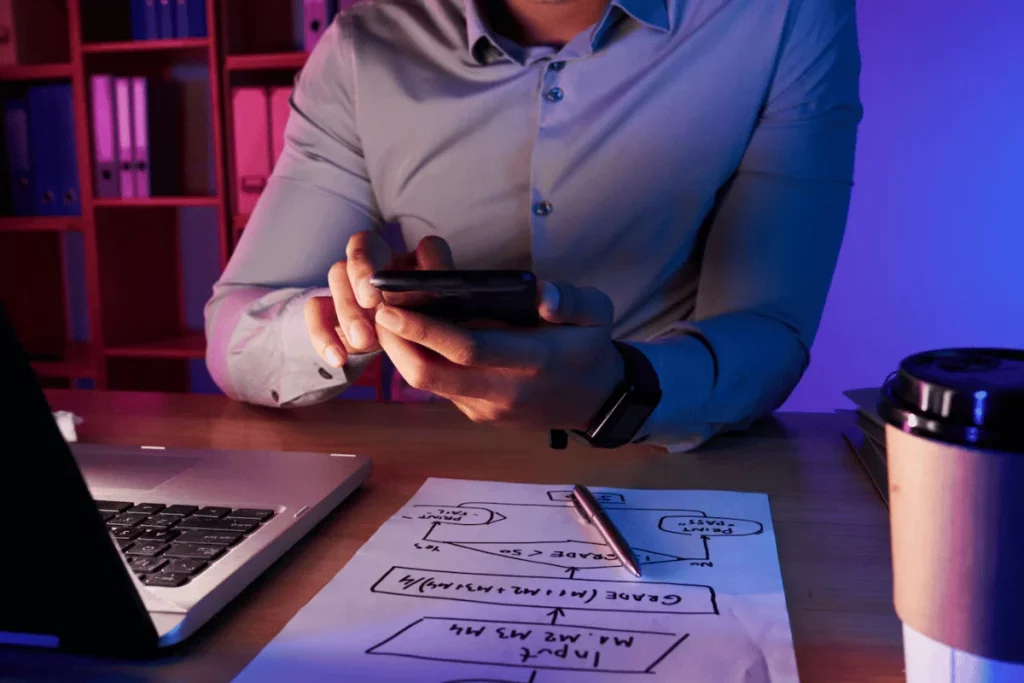 A person sitting at a desk with a laptop and a cup of coffee.