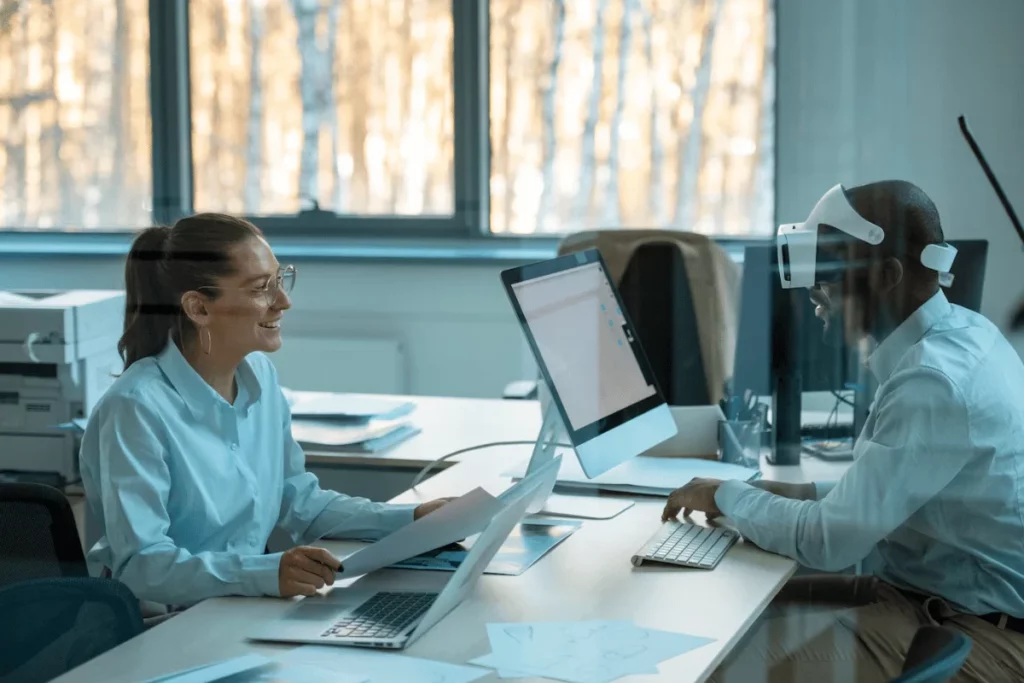 Two people sitting at a desk in front of a computer.