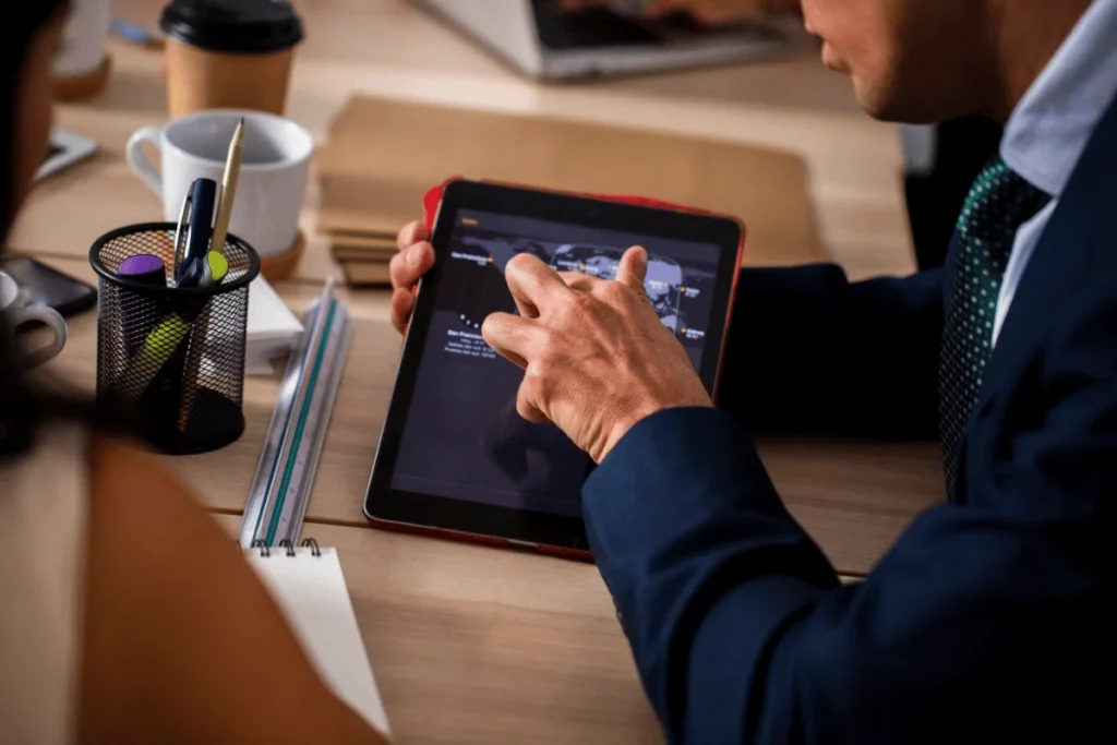 Close-up of a man in a suit working on a tablet during a business discussion.