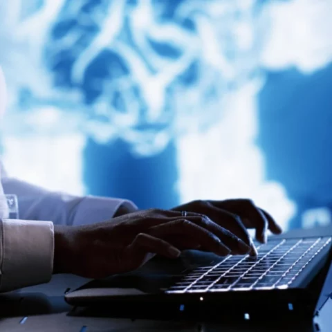 Close-up of a professional working on a laptop with a futuristic digital backdrop.