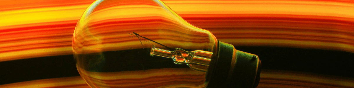 An incandescent light bulb profile with a vibrant, swirling red and yellow background.