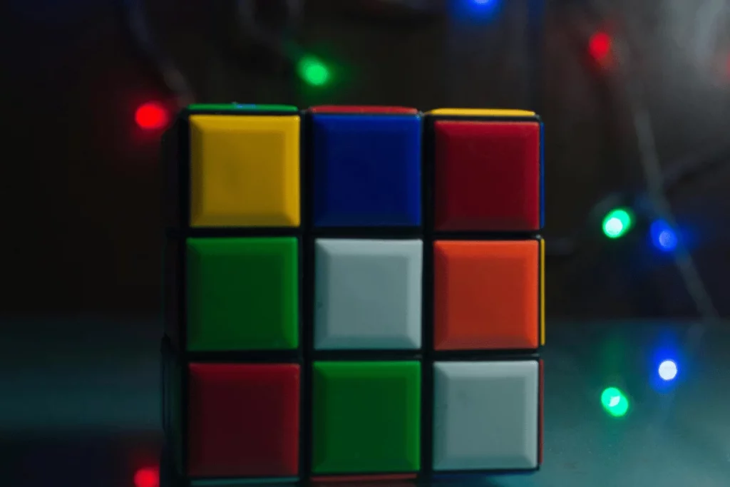 Close-up of a colorful Rubik’s Cube with blurred string lights in the background.