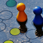 Colorful board game pieces with a die on a blue surface with circle patterns.