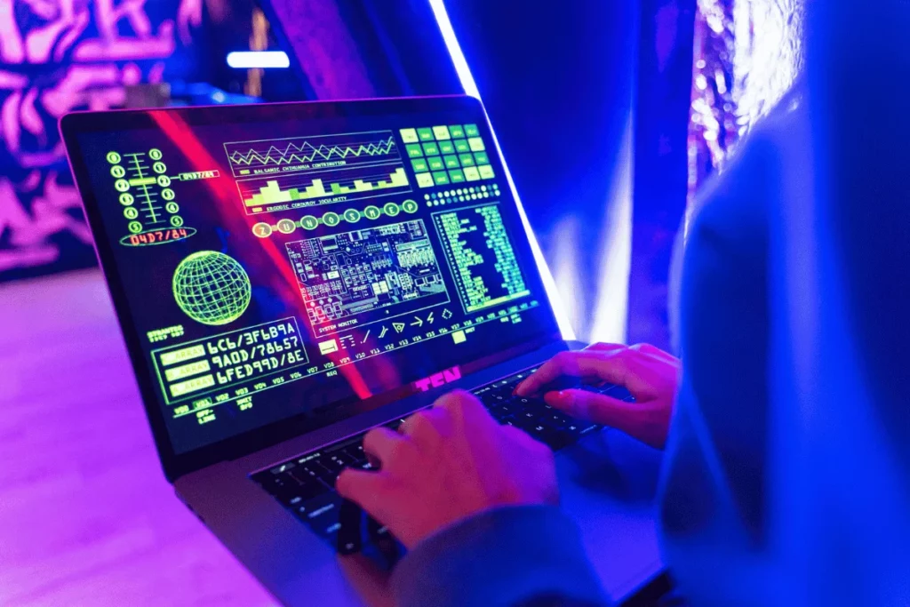 Close-up of hands on a laptop keyboard showing a futuristic data interface in a neon setting.
