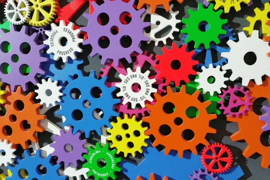 Colorful interlocking gears with some labeled "progress", "diversity", "partnership".