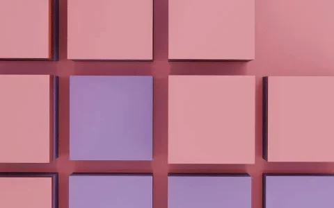 A grid of pink and purple 3D cubes arranged on a soft pink background, creating a modern and minimalist visual composition.