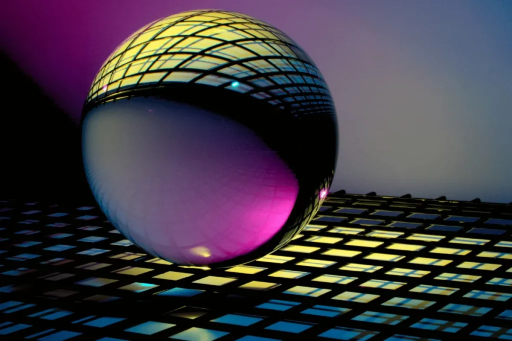 A glass sphere reflects vibrant colors of purple and yellow, set against a patterned grid background with soft gradient lighting.