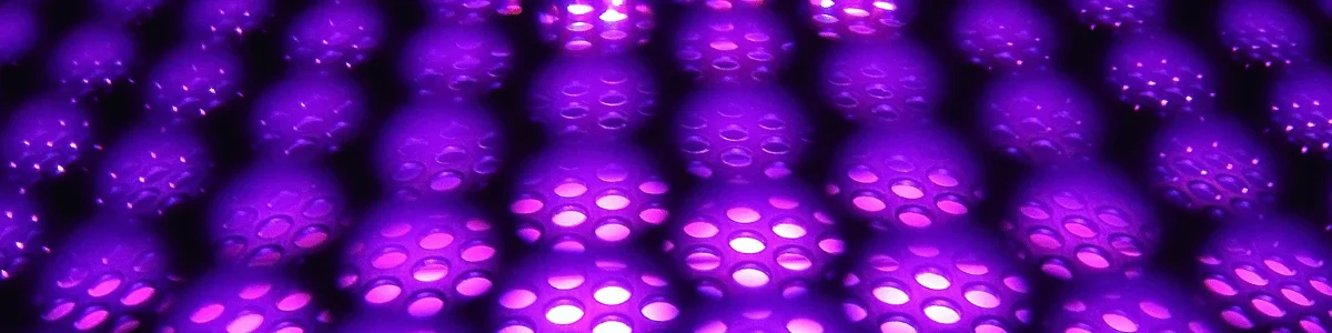 A close-up of a textured surface featuring spherical patterns illuminated in vibrant shades of purple and pink.