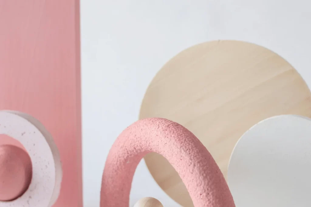 Abstract geometric shapes in soft pink, white, and beige with smooth textures and clean lines.