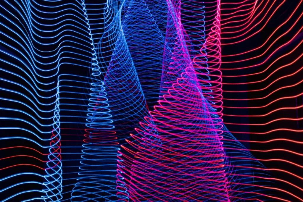Abstract light painting with blue and pink neon wave lines on a dark background.