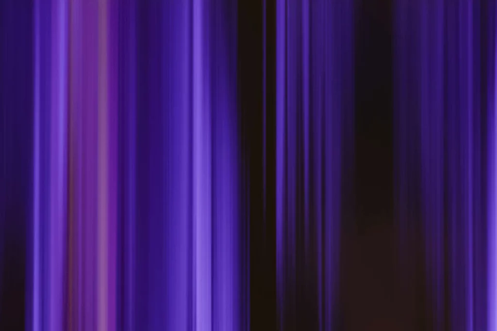 Abstract vertical stripes of purple and blue light creating a modern, blurred pattern.