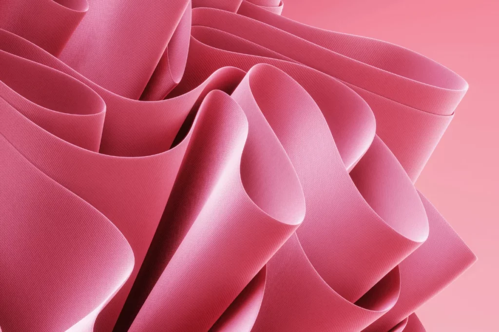 Soft and elegant pink fabric flowing in smooth, undulating waves, creating a delicate texture.