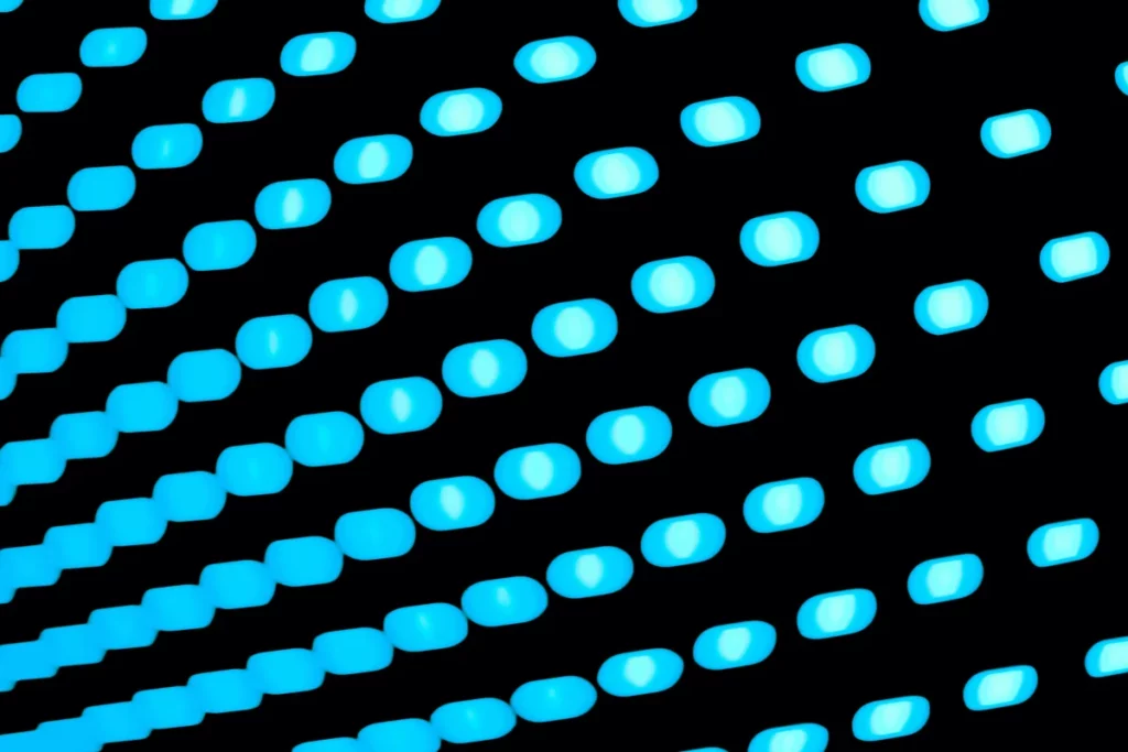 A series of blue glowing dots on a black surface, creating an abstract pattern of light and shadows.