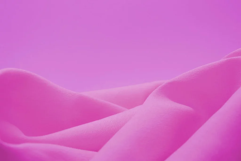 Close-up of soft pink fabric folds against a smooth gradient pink background.