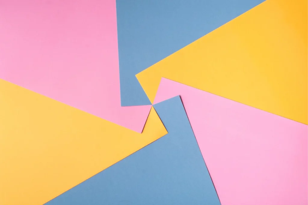 Abstract flat lay of pink, yellow, and blue paper sheets.