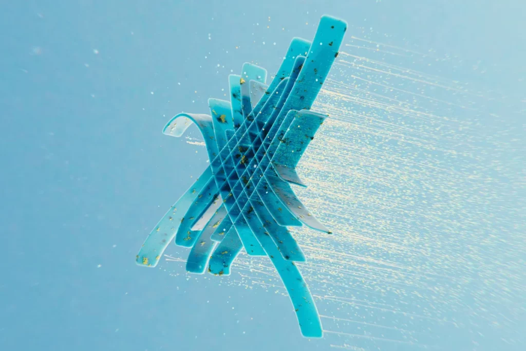 Abstract 3D blue sculpture with gold flecks on light background.